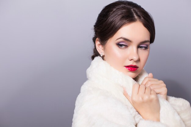 Attractive woman with red lips and white fur coat