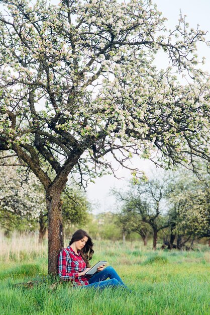 Attractive woman with tablet in blooming garden