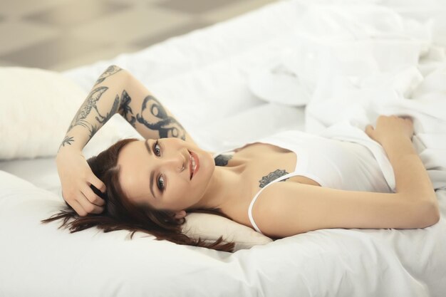 Attractive woman with tattoo lying on the bed