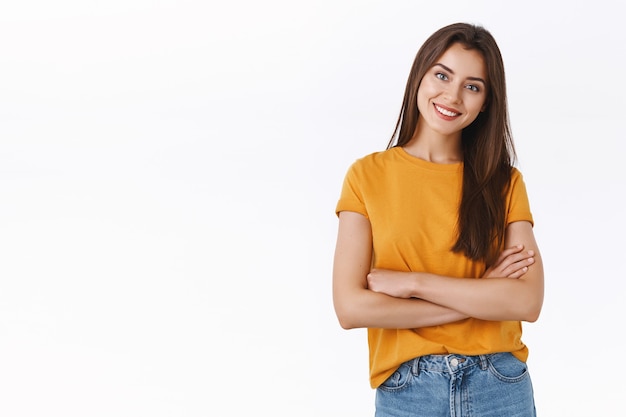 attractive woman in yellow t-shirt cross hands over chest with self-assured, pleased expression, tilt head and smiling satisfied, look at good result, cheering and expressing positive emotions