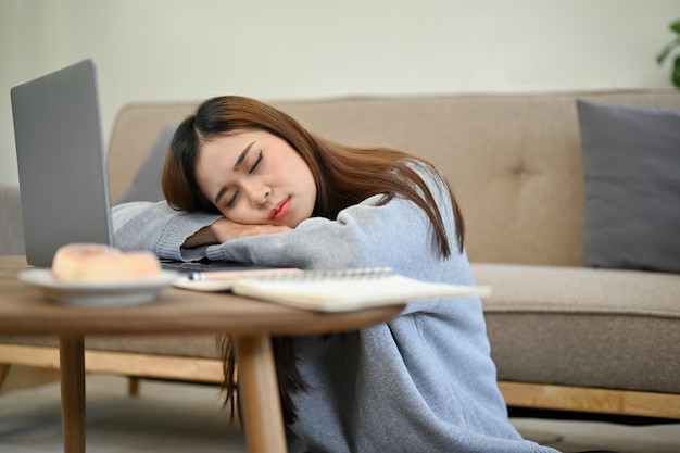 Attractive young Asian woman sleeping leaning on a table fall asleep in the living room