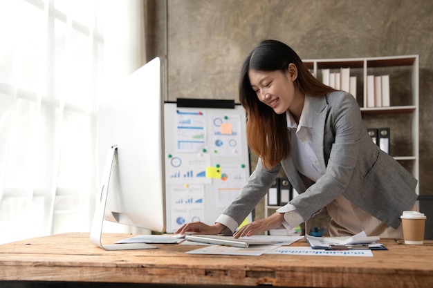 Attractive young asian woman using laptop computer while standing in a office