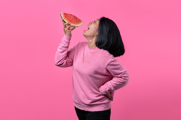 스웨터를 입고 수박 조각을 들고 있는 매력적인 젊은 아시아 여성