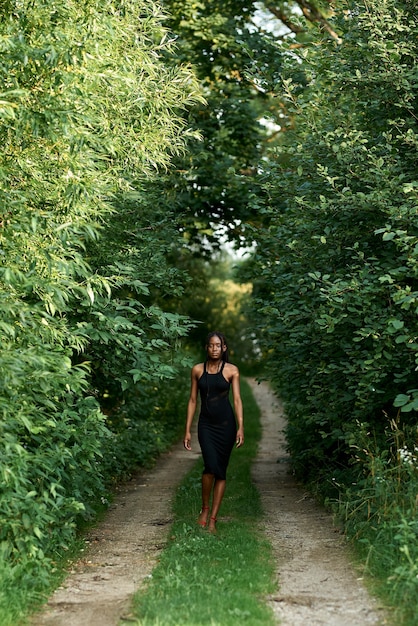 Attractive young black american woman walking away in a forest Mystery mindfulnessDay of earth