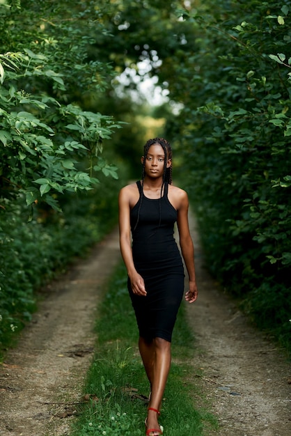 Attractive young black american woman walking away in a forest Mystery mindfulnessDay of earth