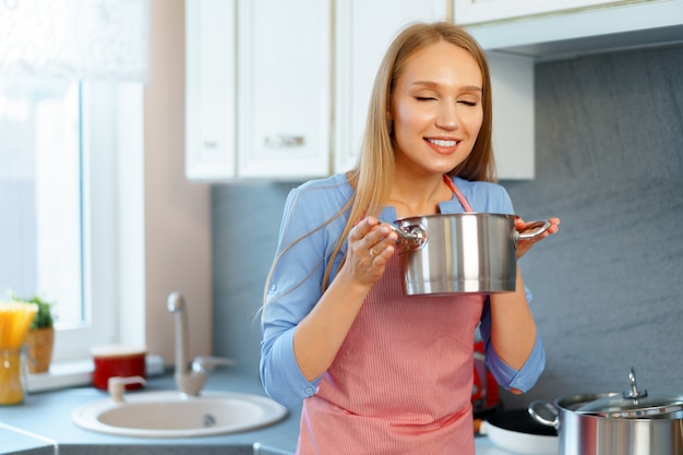 Attraente giovane donna bionda che controlla il cibo cotto