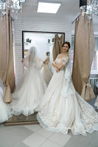 Attractive young bride choosing wedding dress in wedding salon