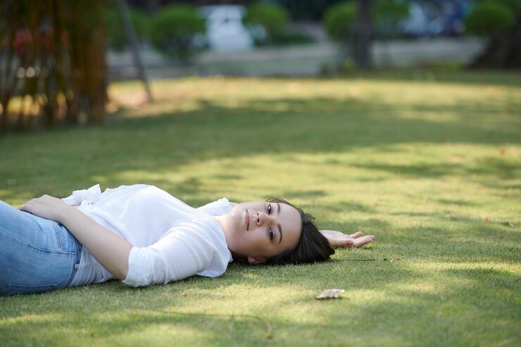 Photo 매력적인 젊은 갈색 머리 도시 공원의 푸른 잔디에서 휴식을 취하고 카메라를 보며 웃고