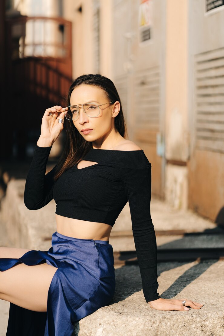 Photo 거리에서 포즈를 취하는 검은 상단과 투명 안경을 쓰고 매력적인 젊은 갈색 머리 여자.