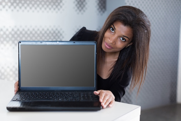 Attractive young businesslady in black strong suite sit at the office table