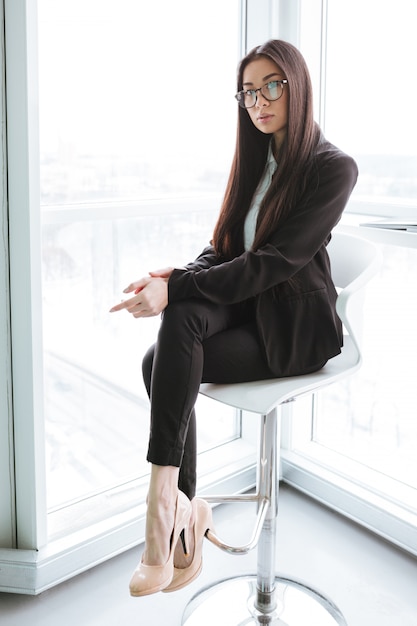 Attractive young businesswoman sitting near the window in office