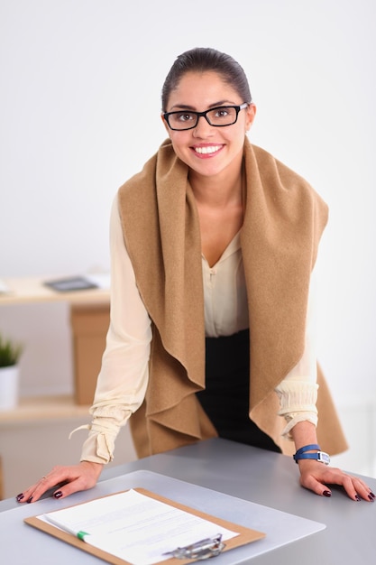 Attractive young businesswoman standing  near desk in office