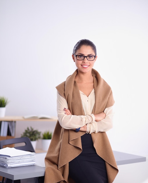 Attractive young businesswoman standing  near desk in office