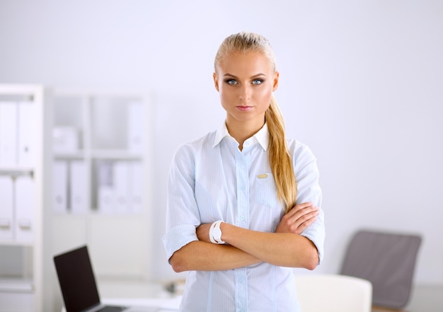 Attractive young businesswoman standing near desk in the office