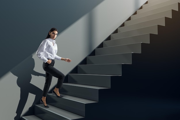 attractive young businesswoman walking up black stairs and concrete wall success worker career growth and up concept