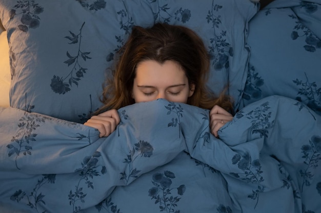 Foto attraente giovane ragazza caucasica che dorme a letto donna avvolta in una coperta fino al naso