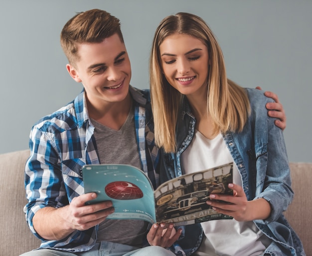 Attractive young couple is reading a magazine.