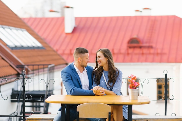 屋外のカフェのテーブルに座って恋をしている魅力的な若いカップル