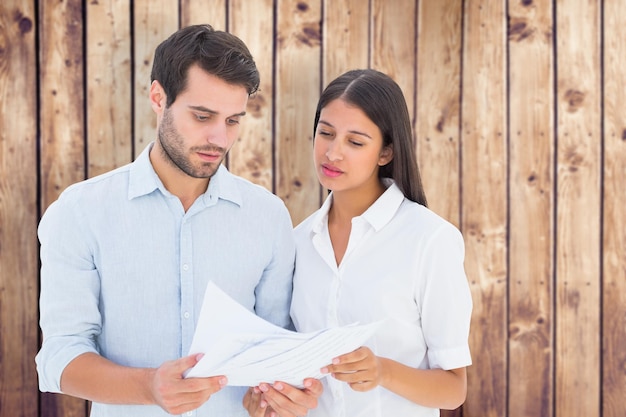 Attractive young couple reading their bills against wooden planks