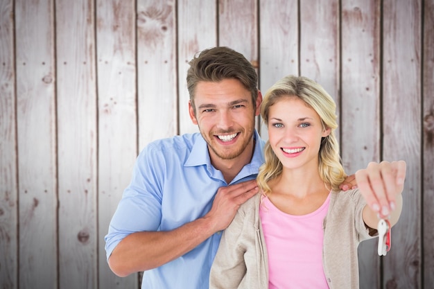 Photo attractive young couple showing new house key against wooden planks