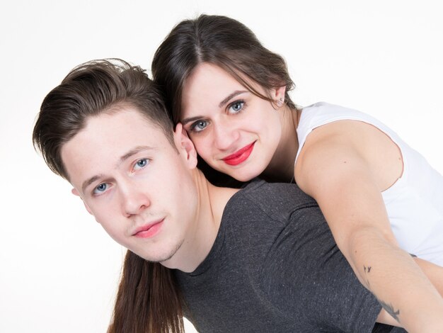 Attractive young couple smiling  on white wall