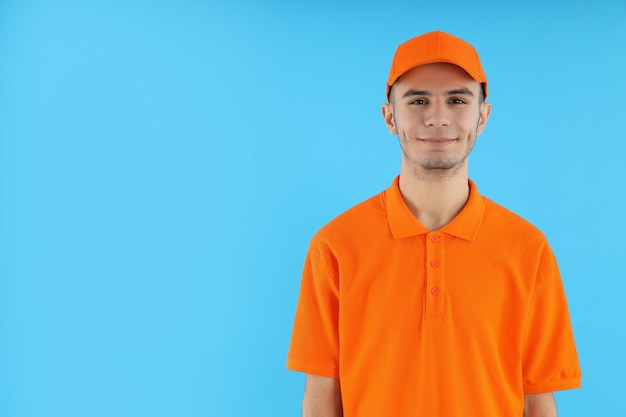 Attractive young delivery man on blue background