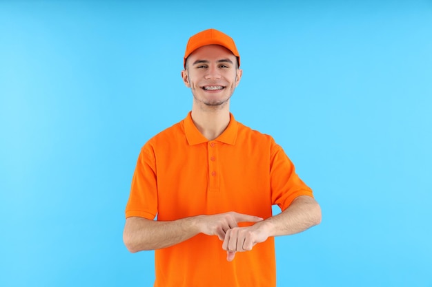 Attractive young delivery man on blue background