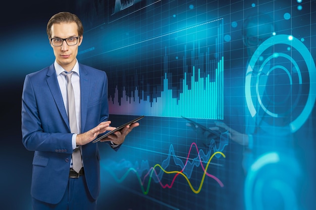 Attractive young european businessman in glasses using mobile\
phone with digital business graph hologram on blurry blue\
background trade finance and analysis concept