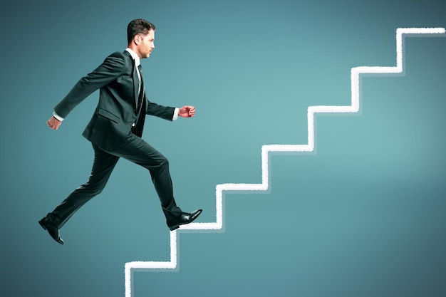 Photo attractive young european businessman running up on abstract stairs on grey background success and career growth concept