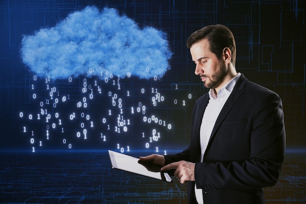 attractive young european businessman using tablet with creative cloud hologram with binary code rain on blurry blue background cloud computing and technology concept