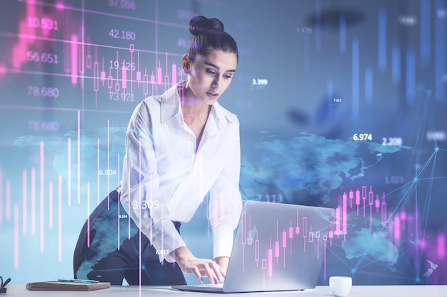 attractive young european businesswoman standing and using laptop with downward purple forex chart on blurry office background crisis and recession concept double exposure