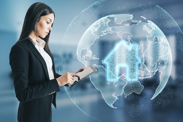 Photo attractive young european businesswoman using tablet with glowing globe and house icon in blurry office interior smart home and innovation concept double exposure