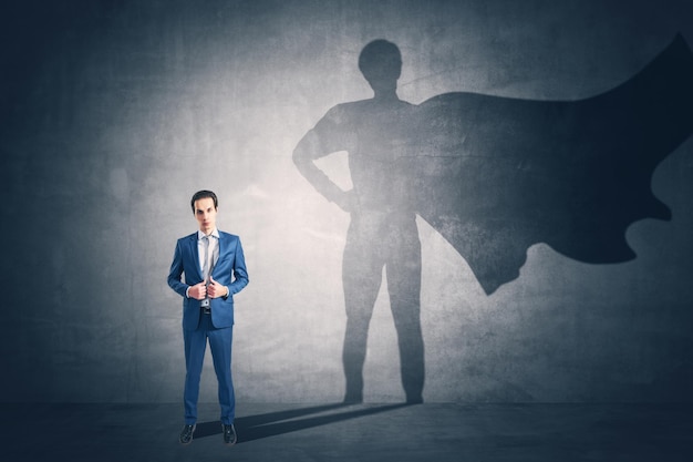 Attractive young european man standing on concrete wall background with cape shadow Leadership success and power concept