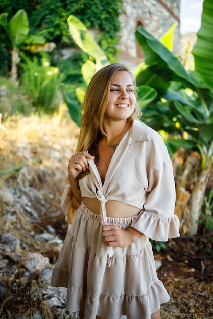 Attractive young fair-skinned woman stands near banana trees in tropical park