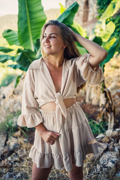 魅力的な若い色白の女性が熱帯公園のバナナの木の近くに立っています