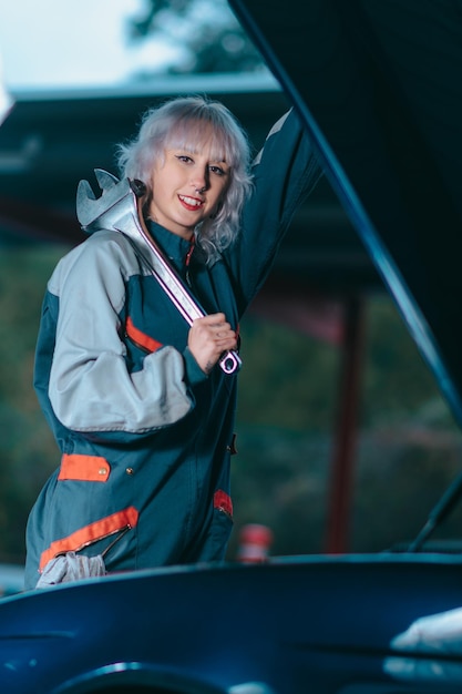 Attractive young female as an auto mechanic posing with a wrench in garage