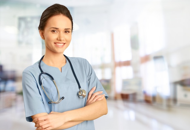 Attractive young female doctor with blurred hospital interior on background