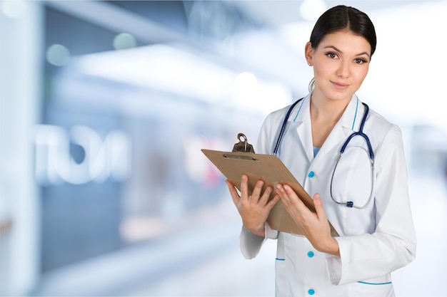 Attractive young female doctor with blurred hospital interior on background