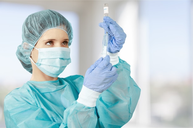 Attractive young female doctor with syringe on blurred hospital interior on background