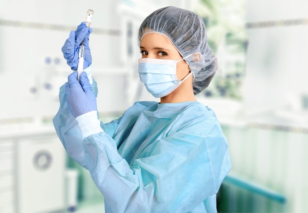 Attractive young female doctor with syringe on blurred hospital interior on background