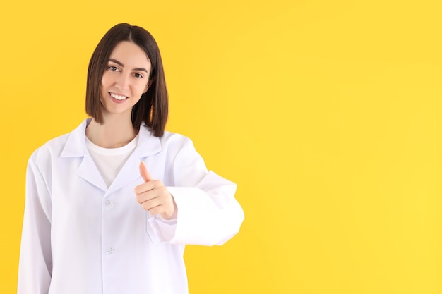 Attractive young female doctor on yellow background