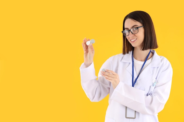 Attractive young female doctor on yellow background