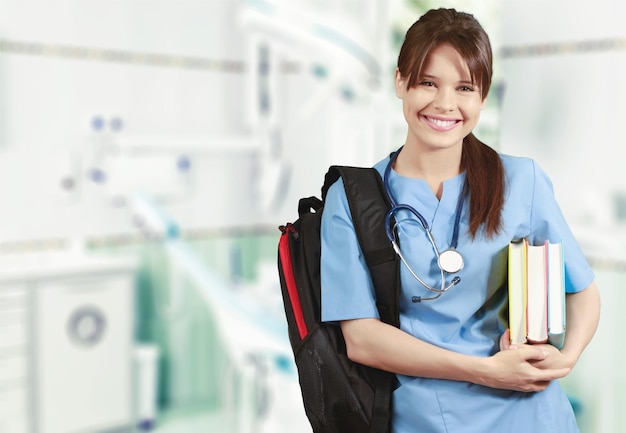 Attractive young female medical student with backpack and books