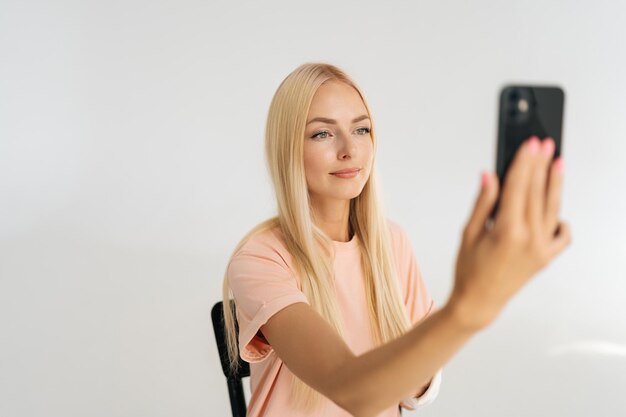 Attractive young female patient with broken arm wrapped in\
plaster bandage talking smartphone making video call having online\
consultation with doctor