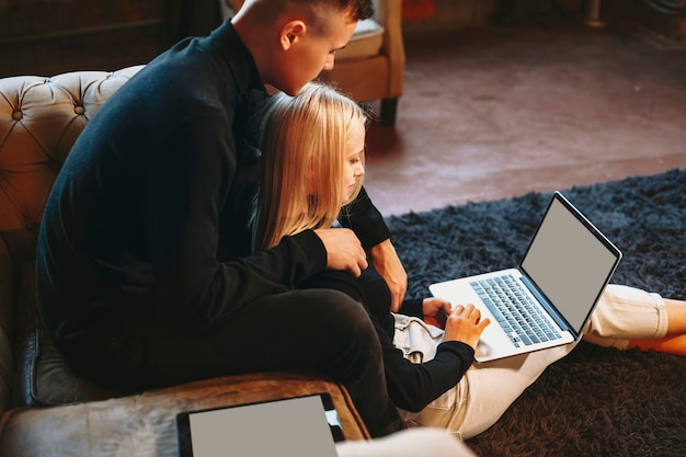 Attractive young female working on the floor at her laptop at home while her boyfriend is embracing her from back.