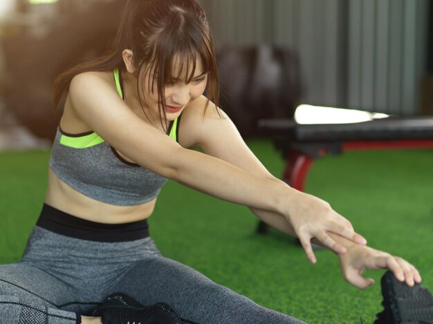 Attraente giovane donna in forma si rinfresca dopo l'allenamento, si esercita allungando la gamba in palestra.