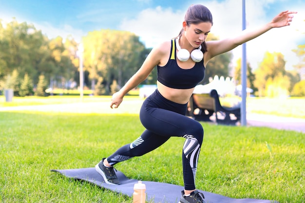 Attractive young fitness woman exercising outdoors stretching exercises