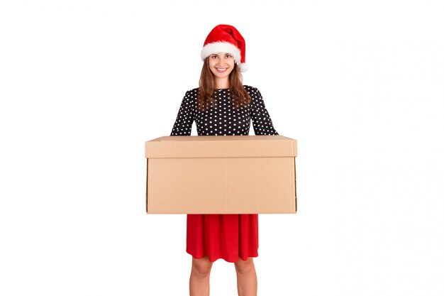 Attractive young girl in christmas hat delivering big cardboard box