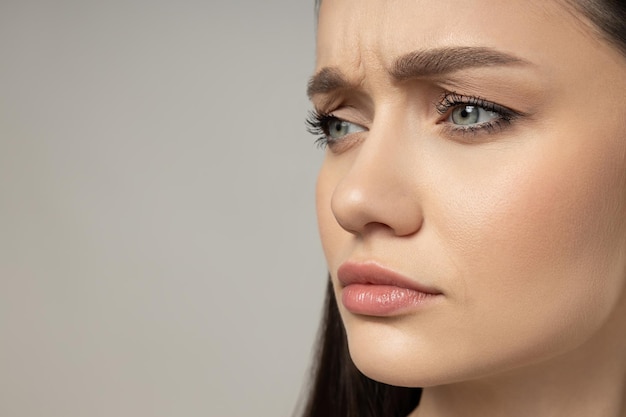 Foto ragazza attraente su uno sfondo grigio concetto di botox