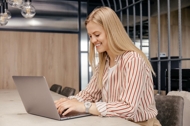 An attractive young girl is working on a laptop in the office